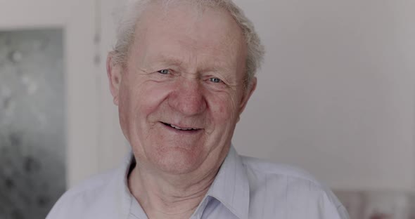 Portrait of Happy Senior Man Smiling and Talking at Camera in Light Room