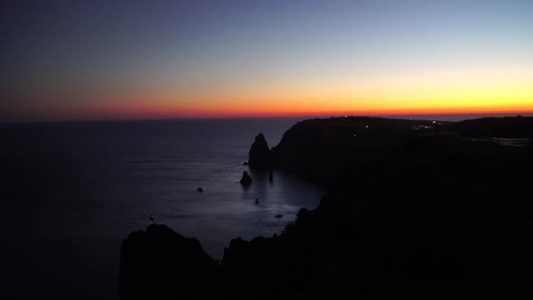 Sunset Over Sea Landscape with Yachts and Rocky Coastline