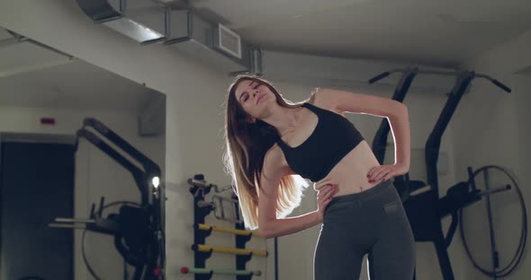 Young Girl with Long Hair Tilts the Torso to Sides in a Sports Studio