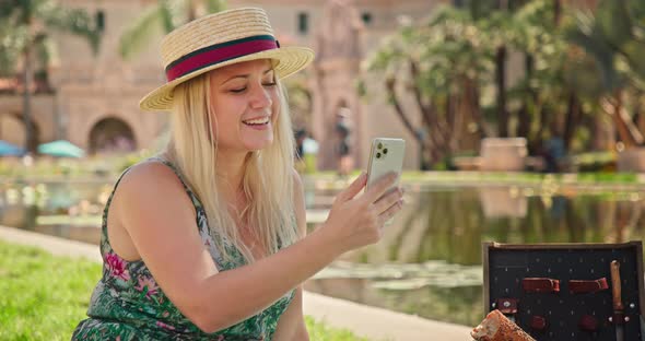 Happy Beautiful Blonde Woman Laughing While Using Smart Phone in Green Park, 