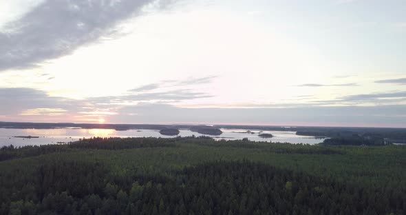 AERIAL ascending, variable speed of lovely sunrise at the horizon with skerries of pine forrest in t