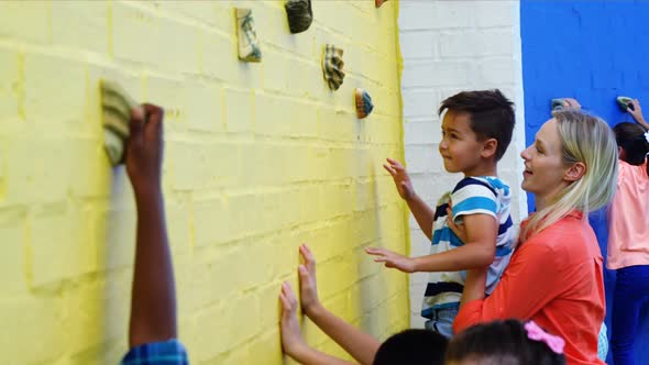 Trainer assisting kids in climbing wall