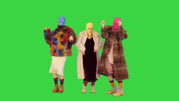 Three Girls in Colored Balaclavas Stand Dancing Slightly on a Green Screen Chroma Key