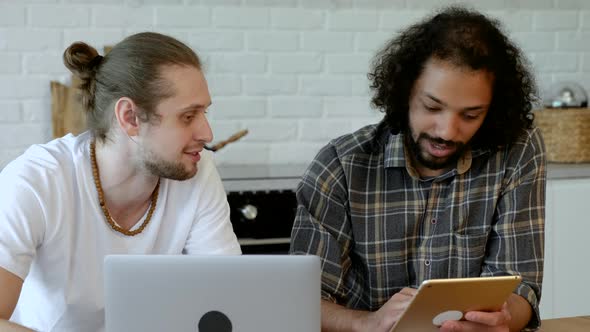 Two Young Male Freelancers Are Working At Home on an Online Project, Using a Laptop