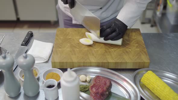 Chefs Hands in Black Latex Gloves Cutting Slices of Lemon Grass in Cutting Board