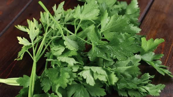 fresh green parsley with droplets rotating on a wooden cutting board