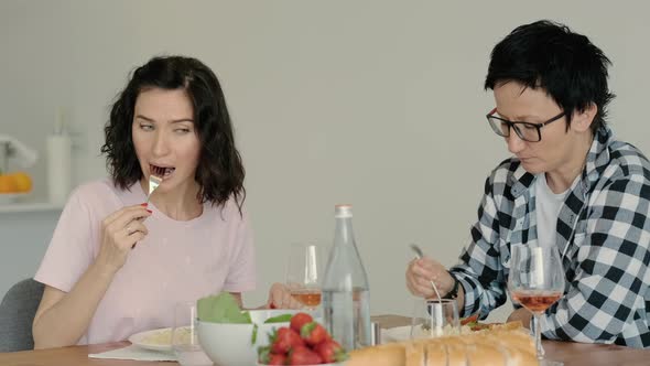 Female Lesbian Couple Eating at Table Having Healthy Food on Kitchen and Wine Rbbro