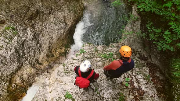 Aerial view of a group of people canyoning and sliding through rocks in river.