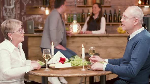 Senior Couple in a Restaurant Clinking Glasses and Drink Wine