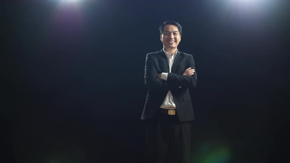 Smiling Speaker Man In Business Suit Crossing His Arms While Standing In The Black Screen Studio