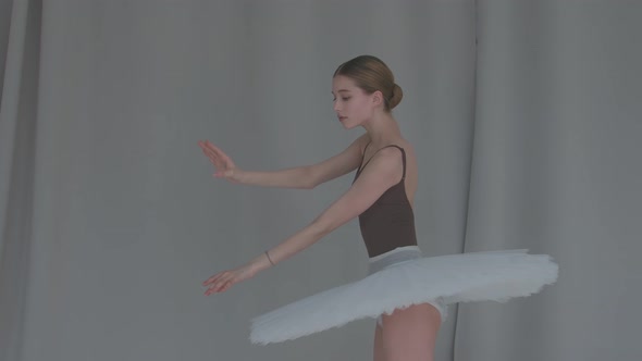 Female Dancer Ballet on a Light Coloured Background Performs Smooth Movements with Her Hands