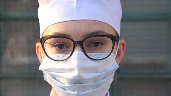 Portrait of Young Female Doctor with Medical Face Mask Looks at Camera