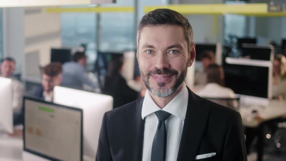 Portrait of Adult Business Man Boss Standing in Office Smiling Looking at Camera While Employees are