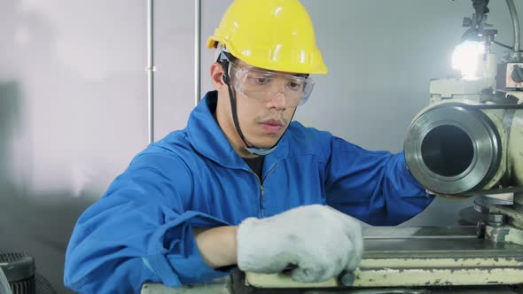 Asian mechanical technicians worker wearing protective helmet working on milling machine in factory.