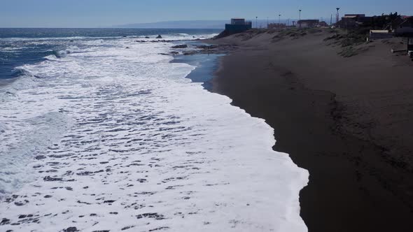 Aerial: infiernillo beach aerial view of a black sand beach on a sunny day drone shot with beach wit