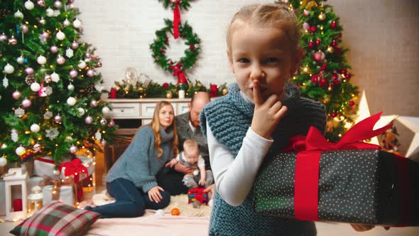 NEW YEAR - Daughter Is Shaking a Gift and Putting a Finger To Her Lips