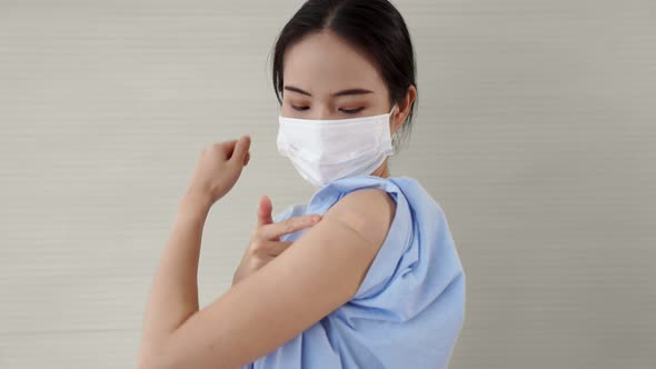 Young Asian Woman Showing COVID19 Vaccine Bandage Merrily