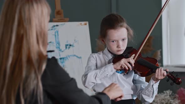 A Girl Learning Playing Violin with Her Teacher