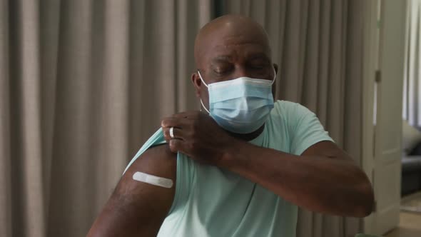 African american man showing plaster on arm where he was vaccinated against coronavirus