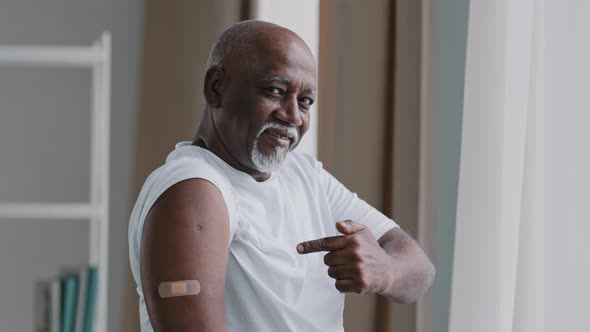 Happy Elderly African American Man Show Adhesive Bandage on Shoulder After Vaccination Smiling