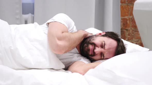 Beard Man with Neck Pain Trying to Relax in Bed