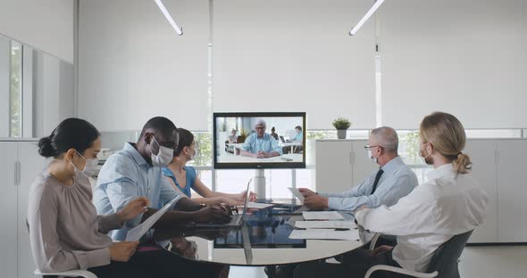 Smart Business Team in Face Mask Have Online Video Call on Monitor in Office
