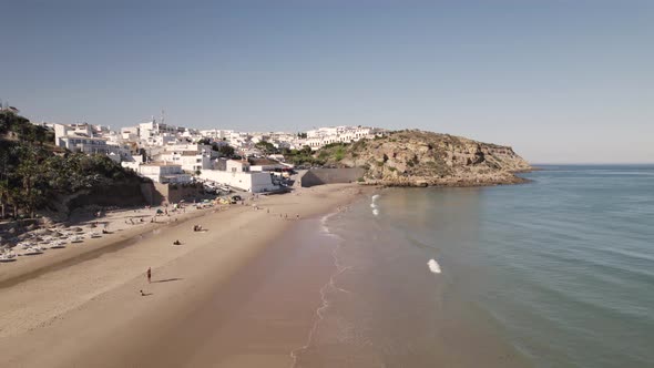 People at the Burgau sand beach enjoying small ocean waves and sun