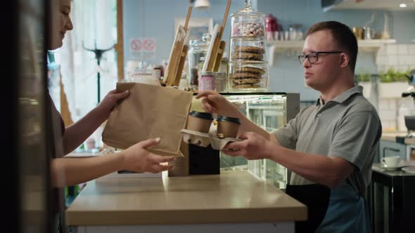 Caucasian man with down syndrome giving take away food to a female client. Shot with RED helium came