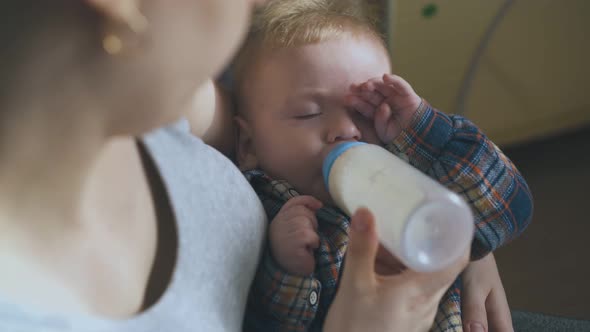 Happy Mommy Rocks Son Eating Milk Mix in Spacious Room