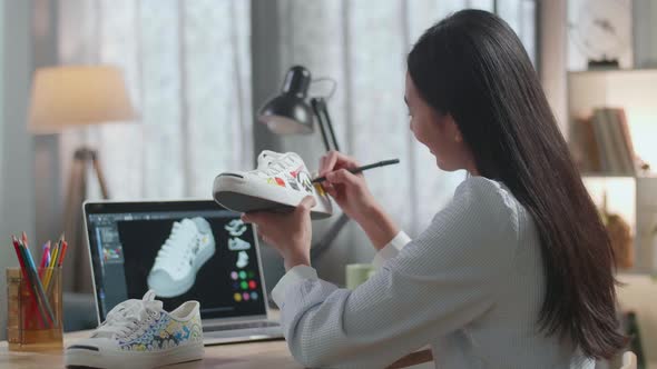 Female Footwear Designer Looking At A Laptop And Putting Coloured Unique Patterns On Sneakers