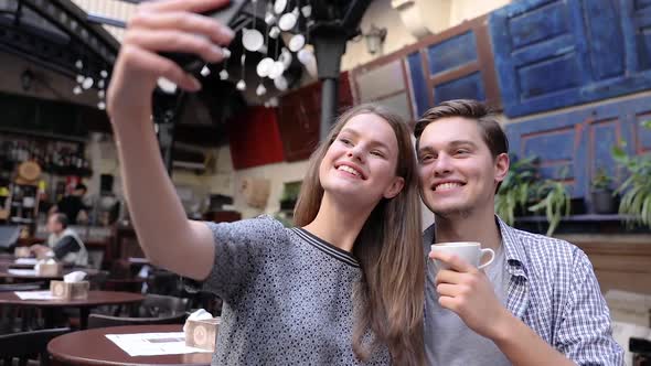 Couple Making Photo On Mobile Phone At Coffee Shop