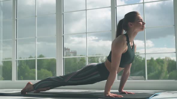 Young Woman Is Doing Yoga in a White Room Filled with Light the Girl Performs Yoga Stands 