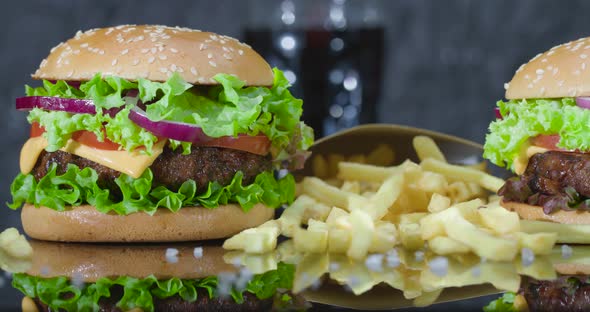 Hamburger, French Fries and Cola in a Glass in the Background, on a Gray Background.