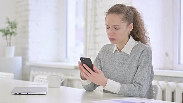 Sad Young Latin Woman Reacting To Loss on Smartphone