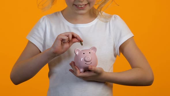 Female Child Putting Coins Into Piggy Bank, Savings and Personal Budget, Finance