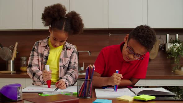 Cute Cheerful Elementary Age African American Siblings Drawing Pictures at Home