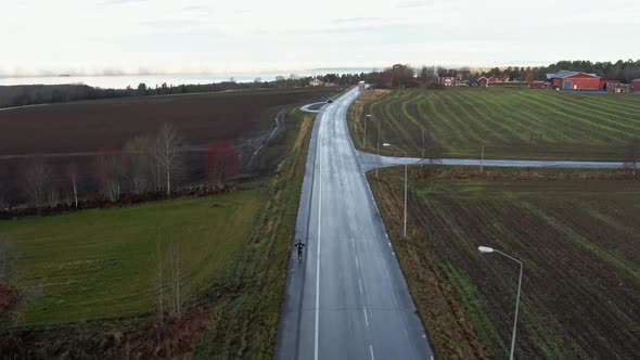 Man Skiing Down Long Isolated Wet Countryside Road Near Ostersund, Sweden. 4K Drone.