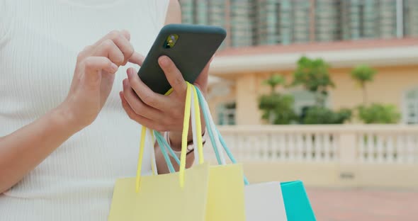 Woman holding shopping bag with cellphone 