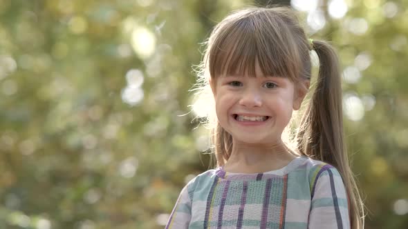 Portrait of Happy Child Girl with Bunch of Yellow Autumn Leaves Smiling in Camera on Bright Blurred