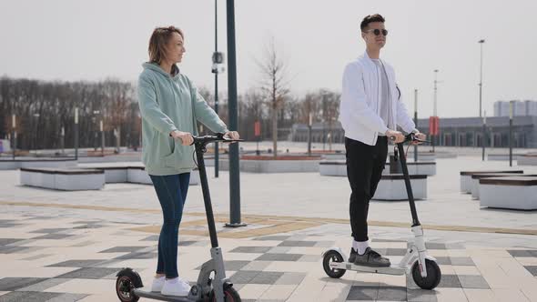 A Man and a Woman Ride an Electric Scooter