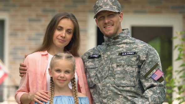 Smiling Army Officer Showing House Key Ring Hugging Happy Wife and Daughter