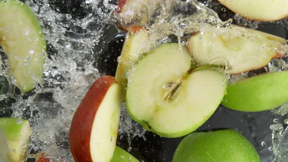 Super Slow Motion Shot of Red and Green Apple Cuts Falling and Splashing Into Water at 1000Fps alt