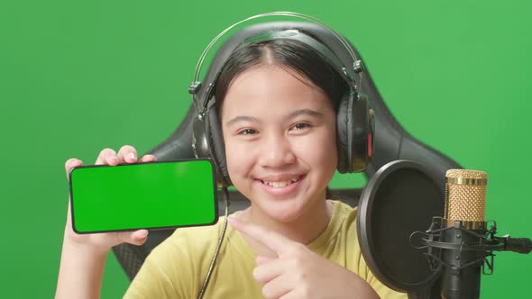 Kid Girl Holding Mobile Phone With Mock Up Green Screen While Live Stream In Green Screen Studio