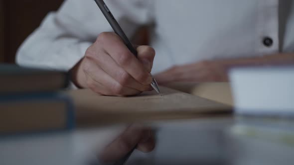 Close up of hand writing notes in personal diary of memories studies in library with book. Education