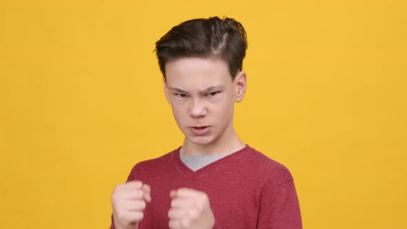 Angry Boy Clenching Fists In Boxing Stance Position Yellow Background