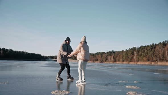 Man Teaching Woman How to Ice Skate on a Frozen Lake on a Sunny Winter Day