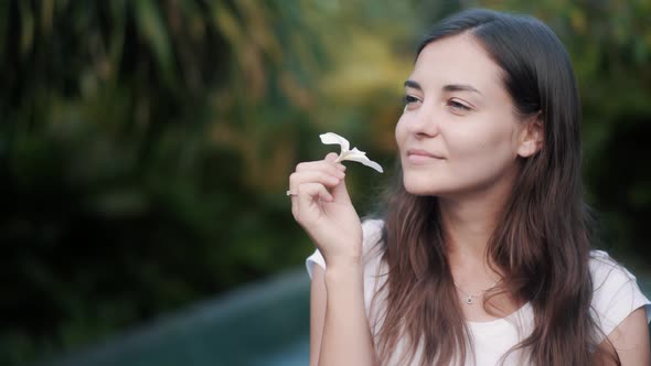 Portrait of Woman with Frangipani in Her Hair and Hand, Sniffs Flower and Smiles