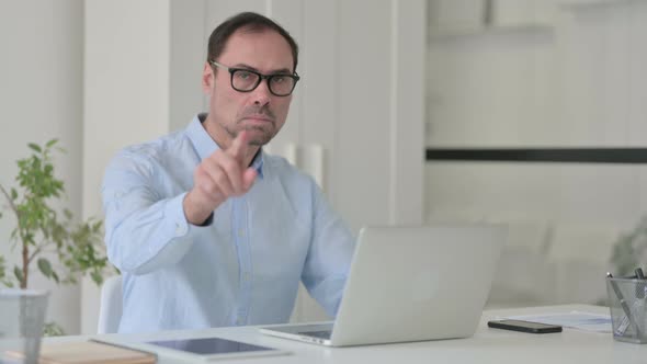 Middle Aged Man with Laptop Pointing at the Camera