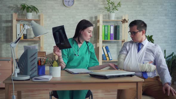 Woman Doctor with Xray in Hand Communicates with the Patient