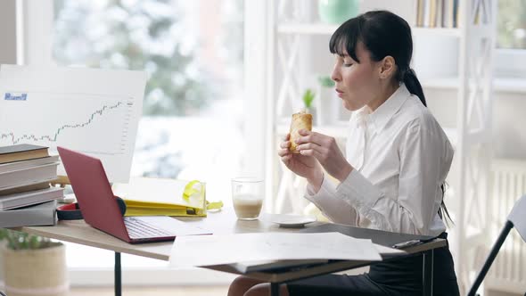 Side View of Young Slim Elegant Woman Eating Lunch at Workplace Indoors